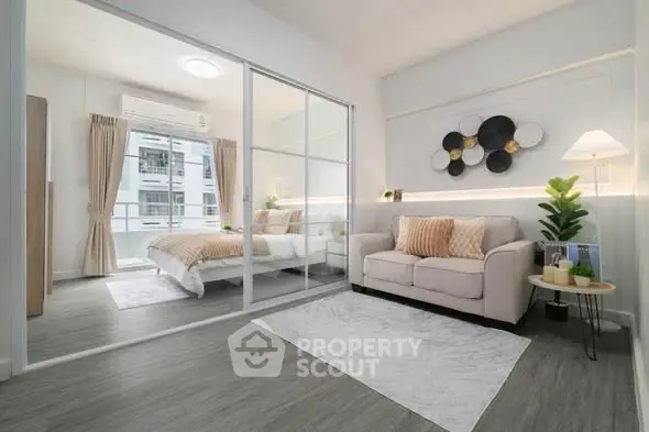 Modern apartment interior with cozy living room and stylish bedroom separated by glass partition.