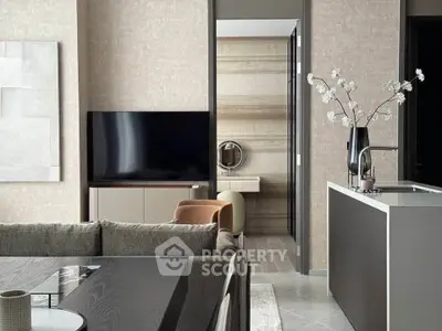 Modern living room with sleek design, featuring a large TV, stylish furniture, and elegant decor.
