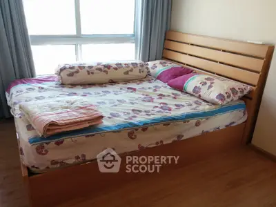 Cozy bedroom with large window and wooden bed frame, perfect for relaxation.