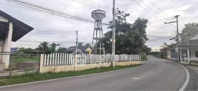Charming rural road with water tower and quaint houses, ideal for serene living.