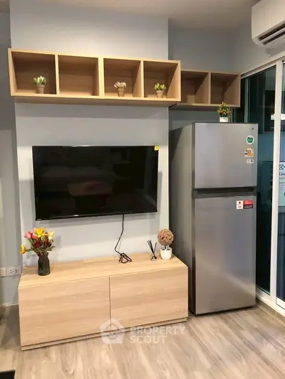 Modern living room with sleek TV setup and stainless steel fridge, featuring stylish wooden shelving and decor.