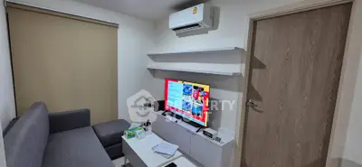 Cozy living room with modern sofa, wall-mounted TV, and air conditioning unit.