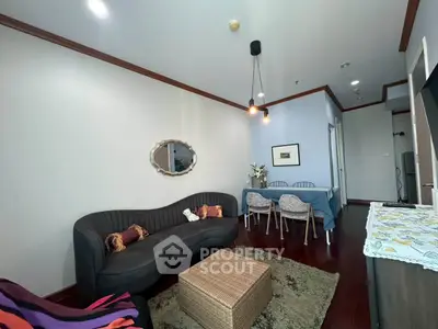 Charming living room with elegant sofa and dining area, featuring modern lighting and cozy decor.