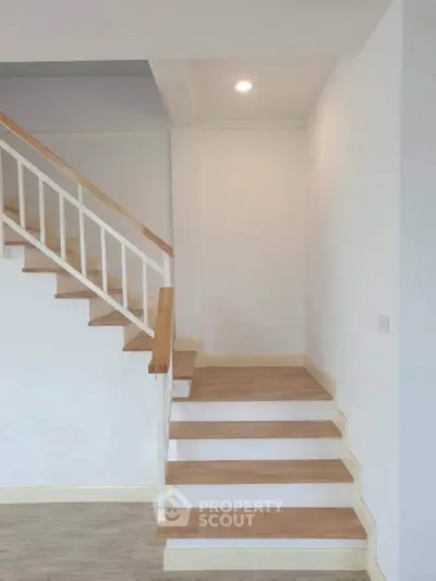 Modern wooden staircase with white railings in a minimalist home interior