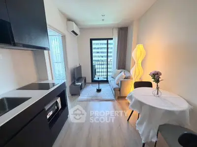 Modern living room with open kitchen, stylish decor, and balcony view in urban apartment.