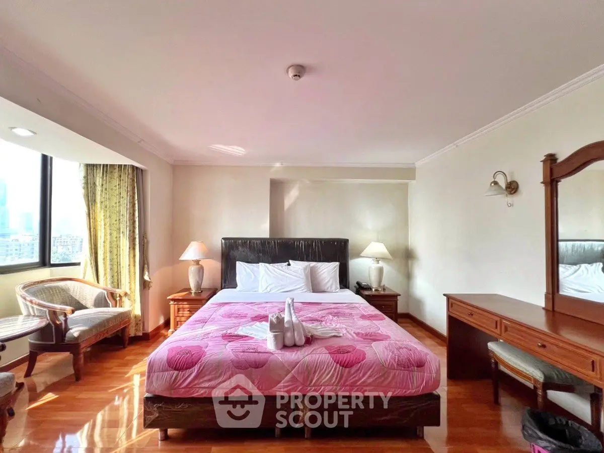Spacious bedroom with city view, elegant furnishings, and natural light.
