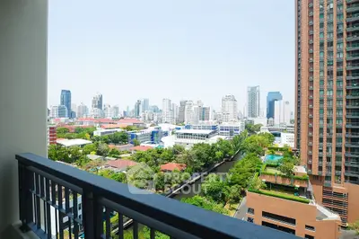 Stunning cityscape view from a high-rise balcony overlooking urban skyline and lush greenery.