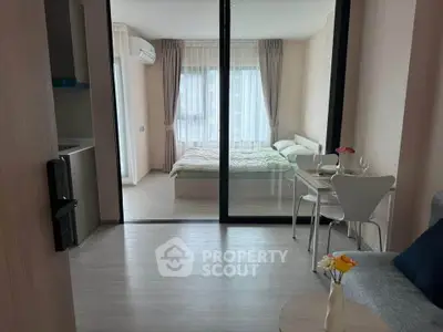 Modern studio apartment with glass partition, cozy living area, and bright bedroom.
