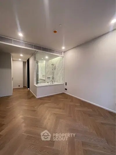 Spacious modern interior with elegant wooden flooring and glass-enclosed shower area.