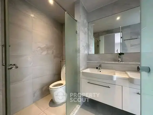 Modern bathroom with sleek fixtures and glass partition in a contemporary home.