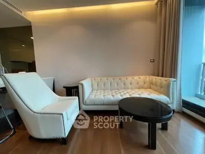 Elegant living room with plush white sofa and armchair, wooden flooring, and modern decor.