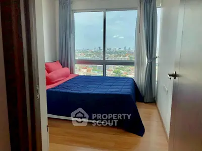 Cozy bedroom with city view and large window, featuring modern decor and wooden flooring.