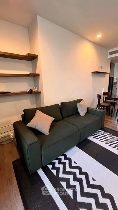 Modern living room with stylish dark green sofa and geometric rug, featuring open shelving and cozy ambiance.