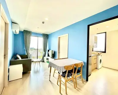 Bright living room with blue walls, modern furniture, and open kitchen layout.