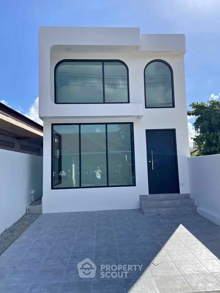 Modern minimalist two-story house with large windows and sleek design.