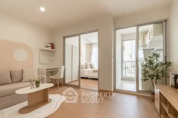 Modern living room with sliding glass doors leading to a cozy bedroom and balcony, featuring stylish decor and natural light.