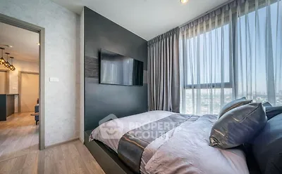 Modern bedroom with large window and city view, featuring sleek decor and cozy bedding.