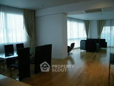 Spacious modern living room with hardwood floors and large windows.