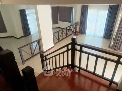 Spacious multi-level living area with elegant wooden staircase and large windows for natural light.