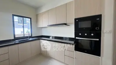 Modern kitchen with sleek cabinetry and built-in appliances, featuring a black countertop and ample natural light.
