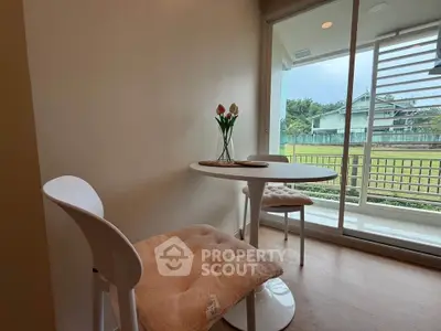 Cozy dining nook with modern chairs and table overlooking lush greenery through glass doors.