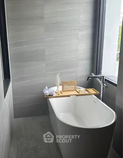 Luxurious modern bathroom with sleek freestanding bathtub and large window view.