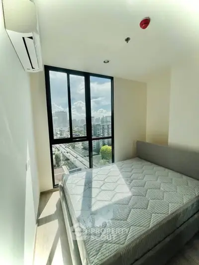 Bright bedroom with large window offering stunning city view, featuring a comfortable bed and modern air conditioning.