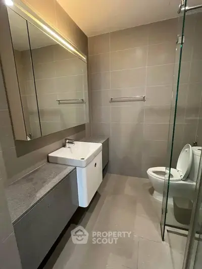 Modern bathroom with sleek design, featuring a glass shower and elegant fixtures.