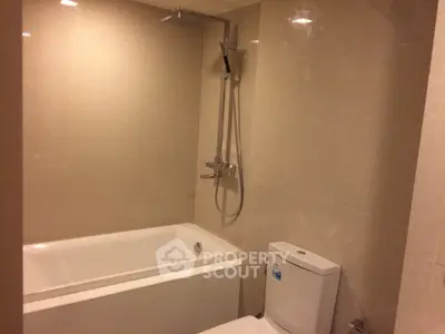 Modern bathroom with sleek bathtub and shower in elegant beige tones.