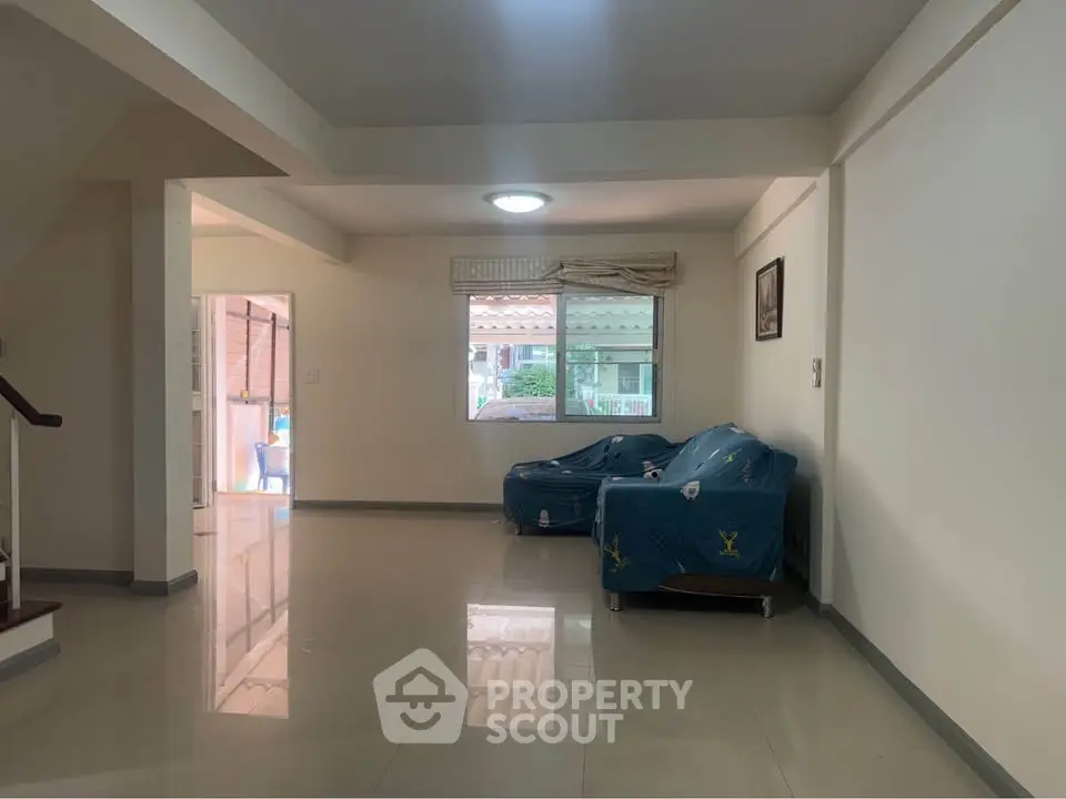 Spacious living room with tiled floor and large window, perfect for family gatherings.