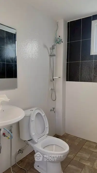 Modern bathroom with sleek black and white tiles and a compact shower area.
