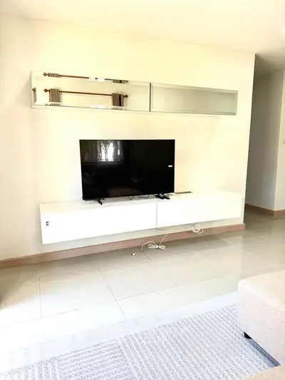 Modern living room with sleek TV setup and stylish wall-mounted storage in a bright, minimalist design.