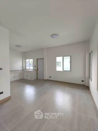 Spacious empty room with large windows and tiled flooring, ready for customization.