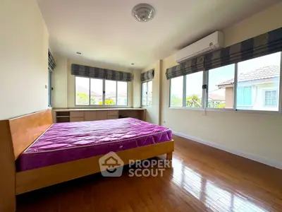 Spacious bedroom with large windows and wooden flooring in a modern home.