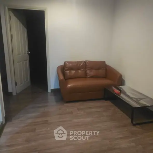 Cozy living room with brown leather sofa and modern coffee table on wooden flooring.