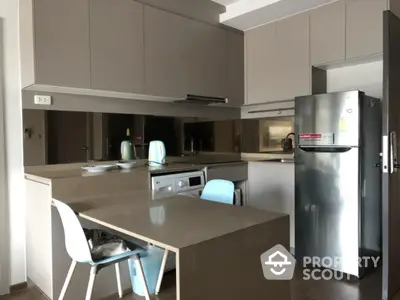 Modern kitchen with sleek cabinetry, stainless steel fridge, and integrated washing machine