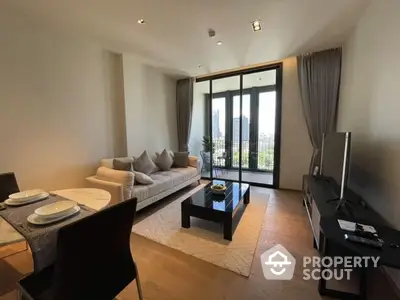 Elegant living room with plush seating, modern decor, and floor-to-ceiling glass doors leading to a sunlit balcony, offering a seamless indoor-outdoor living experience.