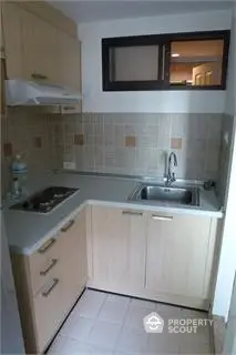 Compact kitchen with modern cabinetry and tiled backsplash in cozy apartment