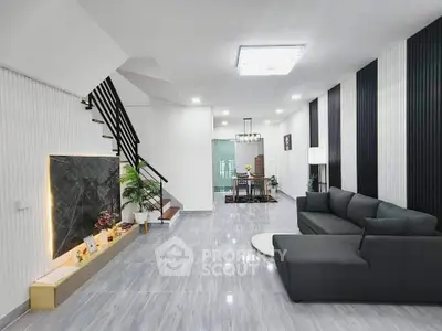 Modern living room with sleek design, featuring a stylish staircase and elegant dining area.