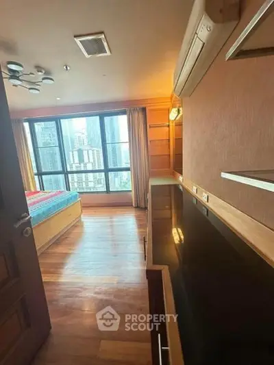 Spacious bedroom with large windows offering stunning city views, featuring elegant wooden flooring and modern lighting.