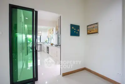 Modern kitchen with green glass sliding door and sleek white cabinetry