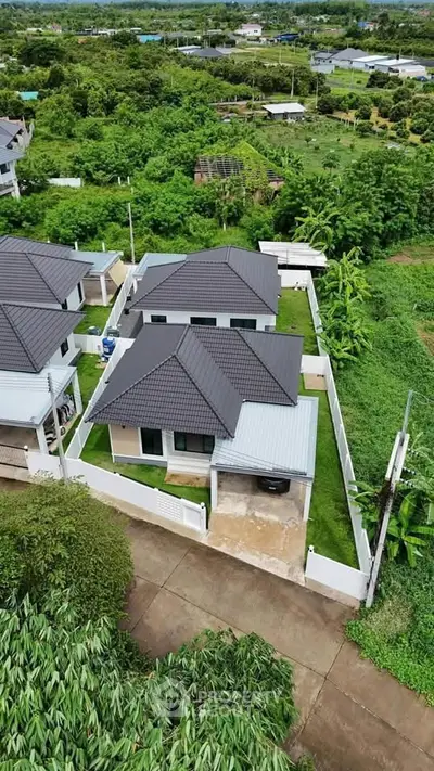 Aerial view of modern suburban homes with lush green surroundings.