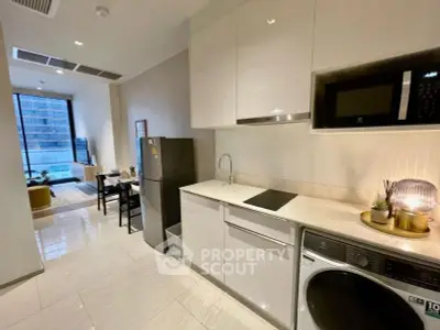 Modern open-plan kitchen with sleek appliances and bright living area in a stylish apartment.
