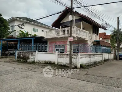 Charming two-story house with balcony and gated entrance in a suburban neighborhood.