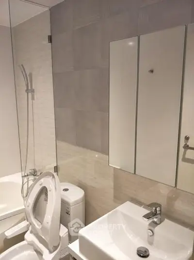 Modern bathroom with sleek fixtures and neutral tiles, featuring a bathtub and mirrored cabinet.