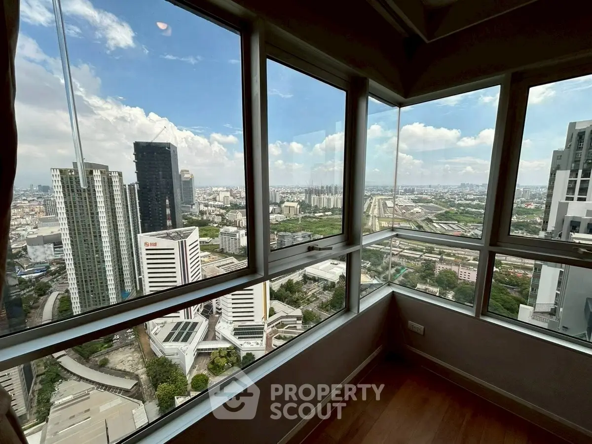 Stunning cityscape view from high-rise apartment corner unit with floor-to-ceiling windows.