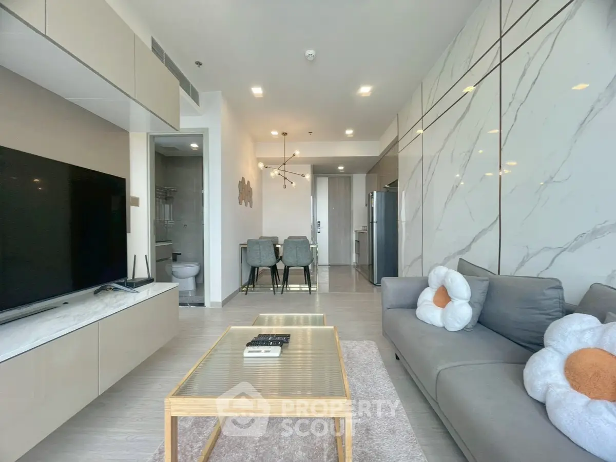 Modern living room with sleek design, marble accent wall, and open kitchen layout.