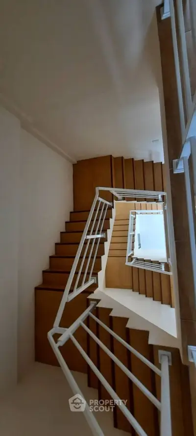 Modern staircase with wooden steps and white railings in a contemporary building.