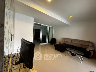 Spacious living room with modern sofa and glass coffee table, perfect for relaxation and entertainment.