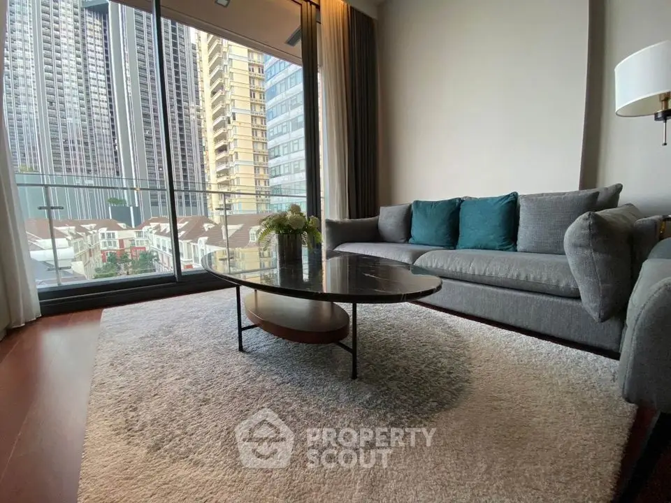 Modern living room with large windows and city view, featuring stylish gray sofa and elegant coffee table.